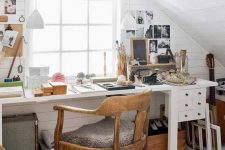 a small and cozy attic home office with white planked walls and a ceiling, a white desk with some drawers, a stained chair and some gallery walls