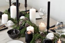 a stylish modern black and white tablescape, with black and white candles, snowy pinecones, metallic cutlery, dark bowls and white plates