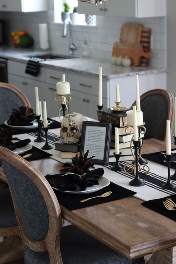 a vintage glam Halloween tablescape with a striped runner, stacks of books, candles in black candleholders, white porcelain and dark feathers