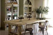 an elegant rustic dining room with a stained table, metal chairs, whitewashed buffets and potted greenery is a welcoming and lovely space