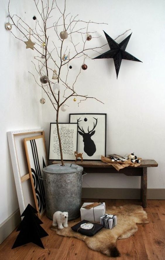 a Nordic entryway space with some artworks, branches with ornaments and a large black star on the wall