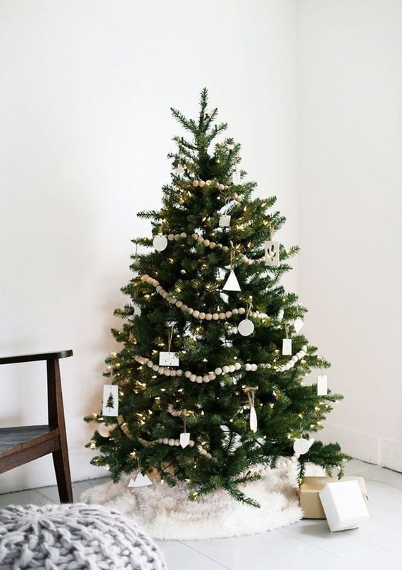 a chic Christmas tree with white ornaments and wooden bead garlands, lights and a faux fur skirt