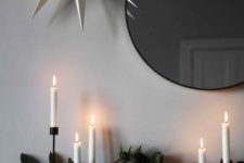 a mantel decorated with eucalyptus, white candles and a large paper star over it all for a Nordic feel