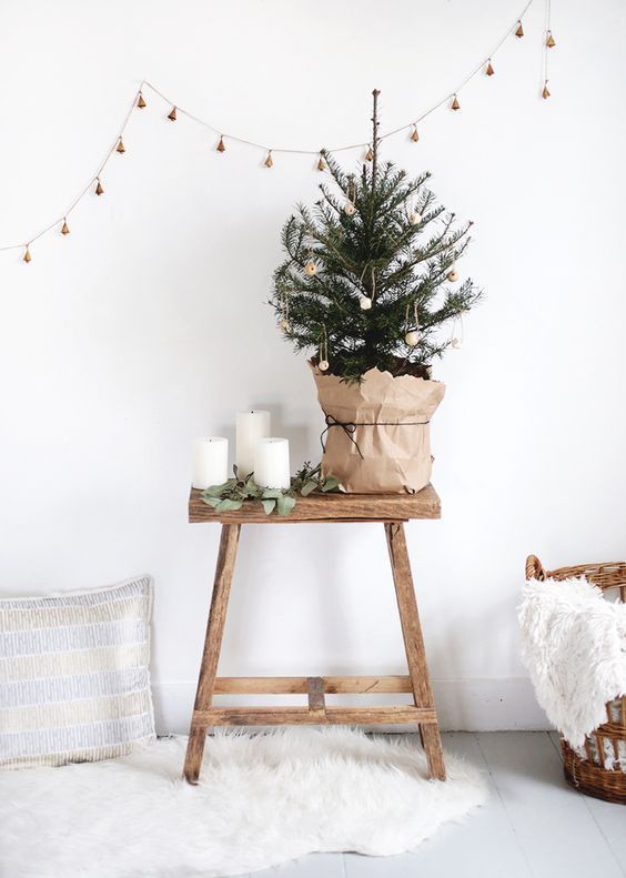 a mini Christmas tree with bead ornaents in kraft paper, candles and eucalyptus plus a bell garland