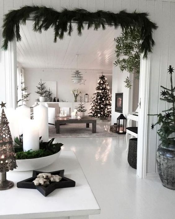 a monochromatic Scandi space with evergreens, white ornaments, candles and candle lanterns looks very modern