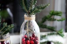 bottles with evergreens, cranberries and faux snow can be used as Scandinavian centerpieces