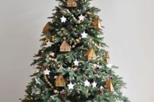 a Christmas tree decorated with wooden bead garlands, pinecones, lights and house ornaments plus white stars