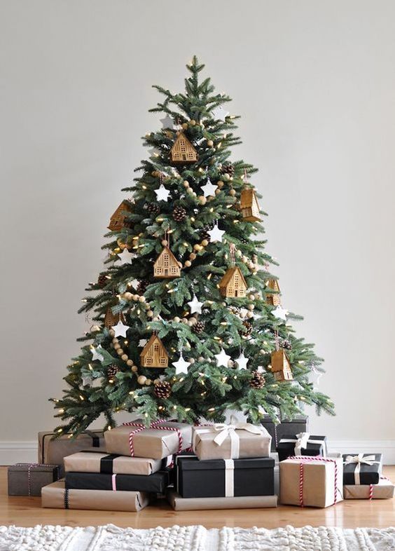 a Christmas tree decorated with wooden bead garlands, pinecones, lights and house ornaments plus white stars