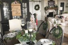 a farmhouse Christmas table with black and white plaid napkins, evergreens and deer printed plates plus candles in candleholders