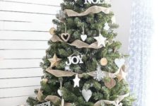 a farmhouse Christmas tree with burlap ribbons, white star and snowflake ornaments and firewood in a red basket