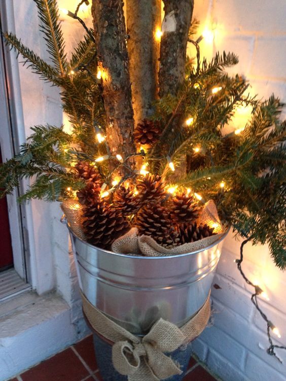 a galvanized bucket with burlap, pinecones, evergreens and branches is a cool rustic decoration for Christmas