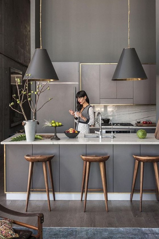 a grey Scandinavian kitchen with sleek lit up cabinets, pendant lamps, white stone countertops and a backsplash