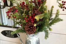 a metal jug with evergreens, pinecones, berries and greenery is a cool Christmas centerpiece