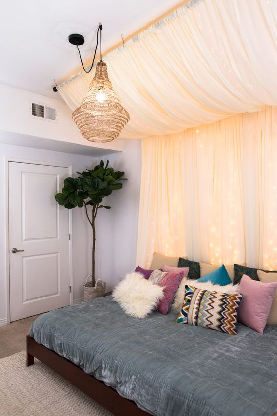 a pastel canopy with lights over the bed plus a wicker lampshade for a boho look