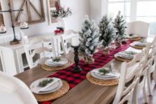 a red plaid runner, flocked Christmas trees in burlap, candles, woven placemats and evergreens on each place setting