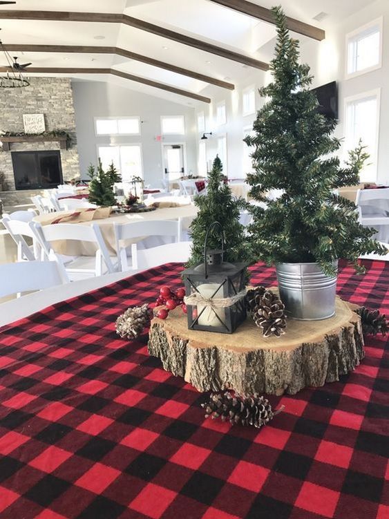 a rustic Christmas centerpiece of a wood slice, pinecones and mini trees in buckets plus a candle lantern