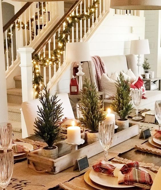 a rustic Christmas centerpiece of a wooden box, mini trees in pots and pillar candles in candleholders