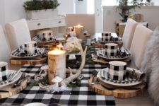 a rustic Christmas table with a buffalo check runner, mugs, napkins, antlers, a candle in a tree stump and some striped napkins