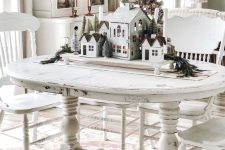 a shabby chic white table and chairs, a stand with houses and bottle brush trees for refined vintage Christmas decor