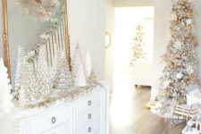 a sophisticated Christmas space in white and gold, with lots of Christmas trees, a flocked tree with white and gold ornaments