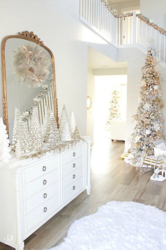 a sophisticated Christmas space in white and gold, with lots of Christmas trees, a flocked tree with white and gold ornaments