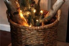 a vine basket with firewood, lights and evergreens is a cool decoration for both indoors and outdoors