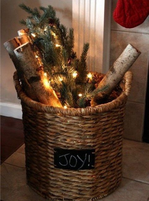 a vine basket with firewood, lights and evergreens is a cool decoration for both indoors and outdoors