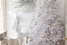 a white Christmas tree with pearly and greige ornaments and beads, a whitewashed twig wreath and white stockings on the mantel