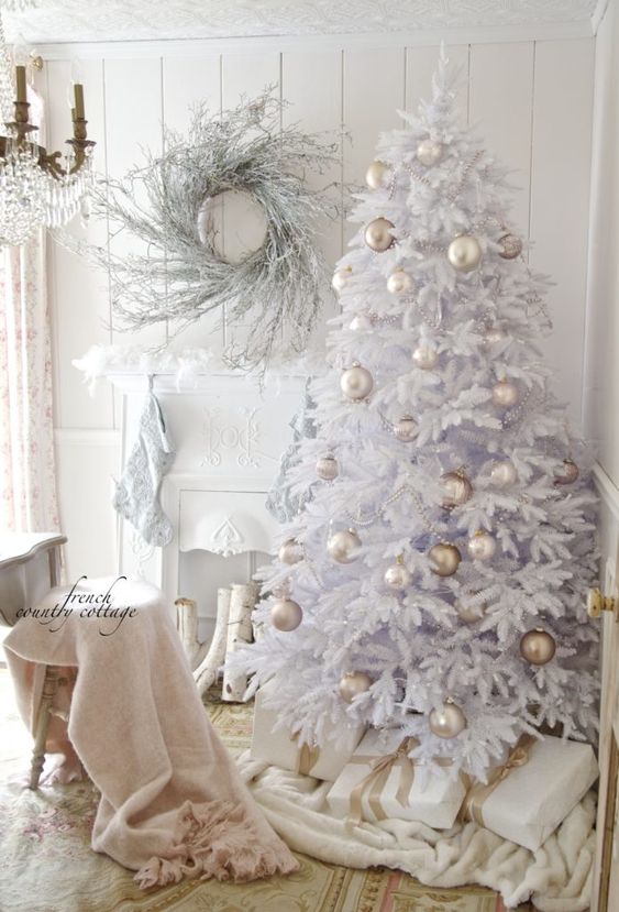 a white Christmas tree with pearly and greige ornaments and beads, a whitewashed twig wreath and white stockings on the mantel