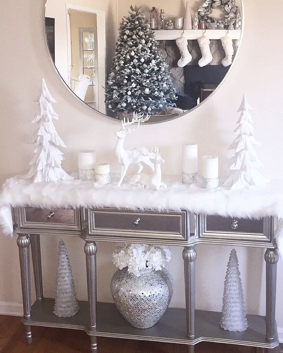 an elegant grey console table with white Christmas trees, white candles, deer and white faux fur is amazing and chic