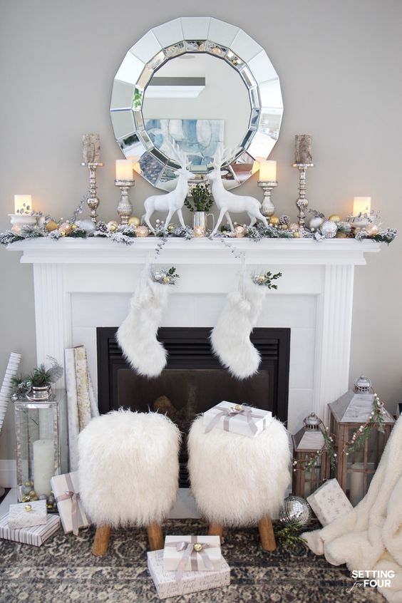 beautiful vintage Christmas decor in white, with deer, faux fur stockings, faux fur stools, candle lanterns, evergreens and gift boxes in white and silver