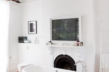 a beautiful bathroom with a vintage fireplace, an artwork, a clawfoot bathtub, a crystal chandelier and some candles