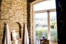a beautiful bathroom with stone walls, a copper bathtub and towels plus a gorgeous view featured