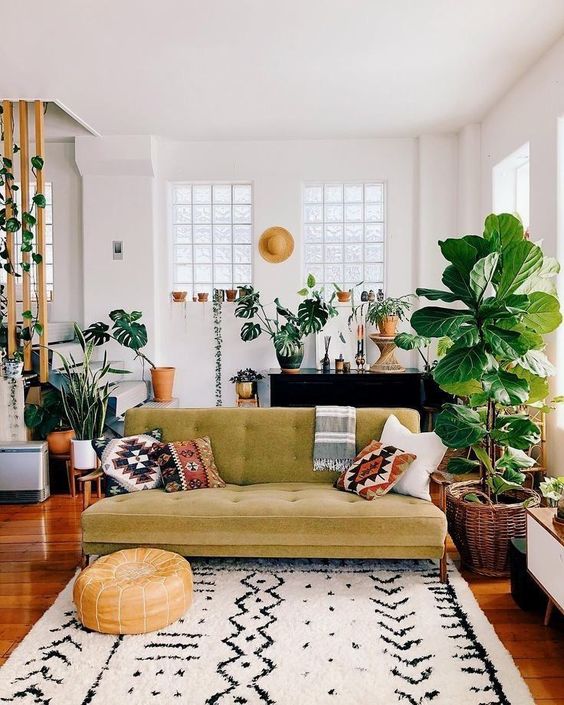 a boho meets mid-century modern living room with prints, a mustard sofa, potted plants and rattan and wicker touches