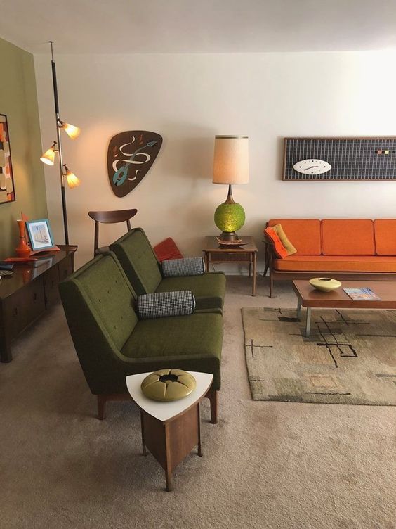 a boho mid-century modern living room with green, rust, neutral items, lamps and quirky artworks