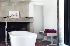 a bold bathroom with catchy floor, a large fireplace of concrete, a metal bench, bright textiles and artwork