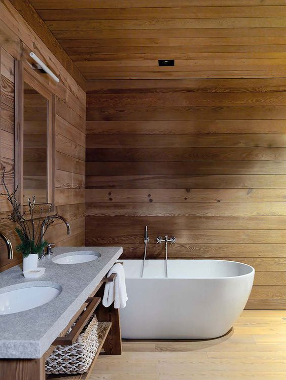 a chalet bathroom clad with wood, with an oval tub, a wooden vanity with a double sink is very simple and very inviting