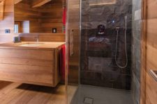a contemporary attic bathroom with sleek wood and a shower space clad with black stone plus built-in lights