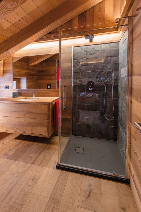 a contemporary attic bathroom with sleek wood and a shower space clad with black stone plus built-in lights