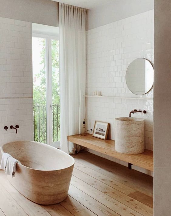 a contemporary bathroom with a wooden floor, a wooden tub, a wooden vanity and a stone sink plus white subway tiles