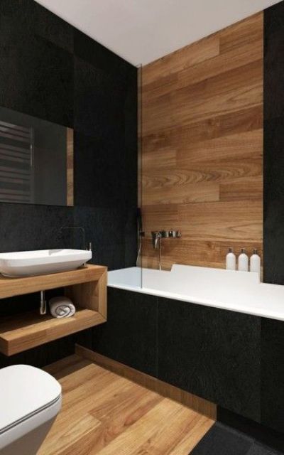 a contemporary bathroom with black tiles, light stained wood, an open wooden vanity, a bathtub with blakc tiles is chic