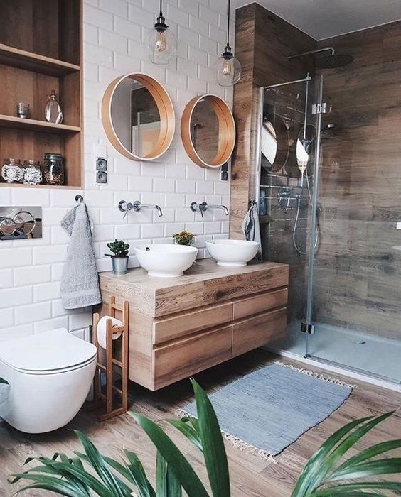 a lovely contemporary bathroom with a wood clad shower space, a wooden vanity, mirrors in wooden frames, laminate floor, a niche clad with wood