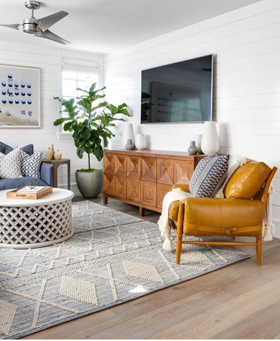 a mid-century modern living room with mustard and blue furniture, an inlay sideboard and a rug with boho embroidery