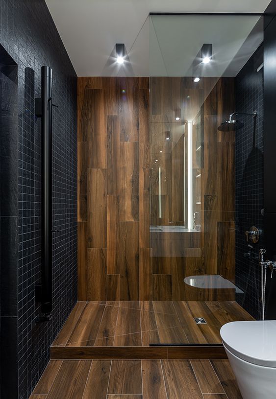 a minimalist bathroom clad with small black tiles and with wood-like tiles for a super elegant and contrasting look