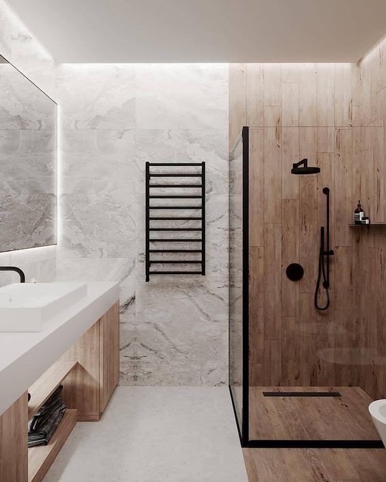 a minimalist bathroom done with light stained wood and white stone tiles, with a wooden vanity and black fixtures
