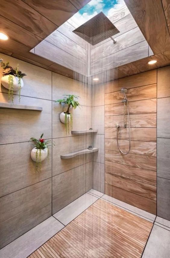 a minimalist bathroom with neutral tiles and wood, with a skylight over the shower space and potted plants on the wall