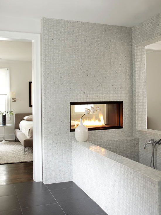 a neutral bathroom with small scale tiles, a double sided fireplace, a bathtub clad with tiles is a chic idea to rock