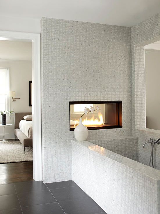 a neutral bathroom with small scale tiles, a double-sided fireplace, a bathtub clad with tiles is a chic idea to rock