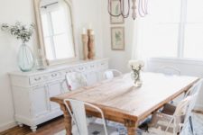 a neutral shabby chic meets rustic dining room with a wooden table, white metal chairs, a shabby chic sideboard and a vintage chandelier