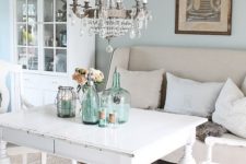 a pastel shabby chic dining room with blue walls, white shabby chic furniture,a  crystal chandelier, blue bottles and jars